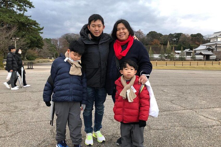 A family of three standing in a public square with a historic building in the background. 5