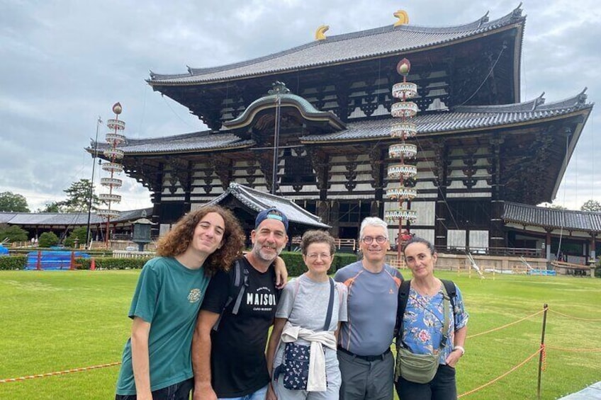 A group of people standing in front of a traditional Japanese building with a curved roof and multiple tiers. 1