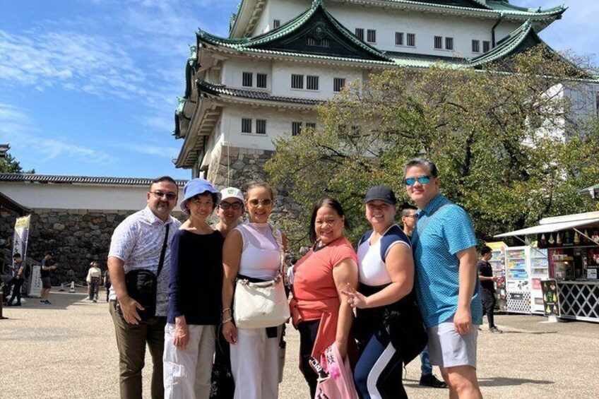 Eine Gruppe von Personen posiert vor einem traditionellen japanischen Gebäude mit grüner Dach und weißen Wänden. 1
