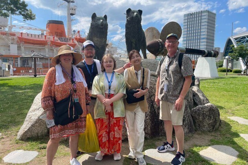 A group of people standing in front of a bear statue and a cannon. 1