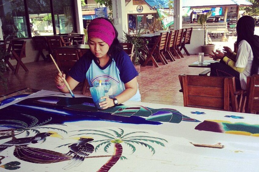 A person painting on a table with a large canvas. 4