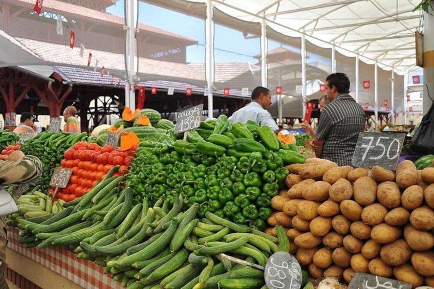 A market with fresh produce, including cucumbers, tomatoes, and potatoes, with price signs. 3
