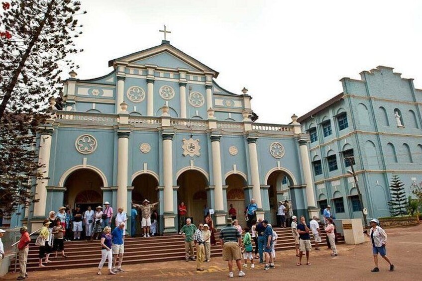 A large church with a blue facade, multiple arches, and a clock tower. 1
