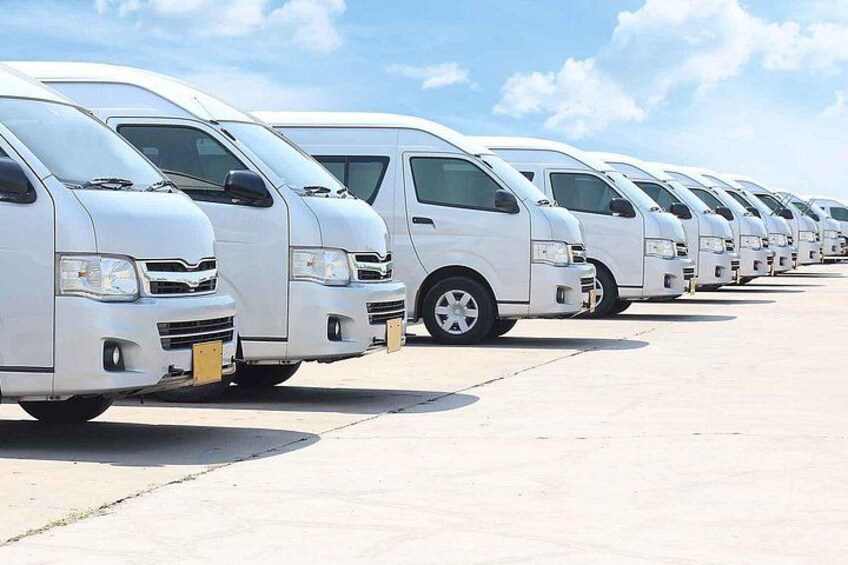 A row of white vans parked in a lot. 2