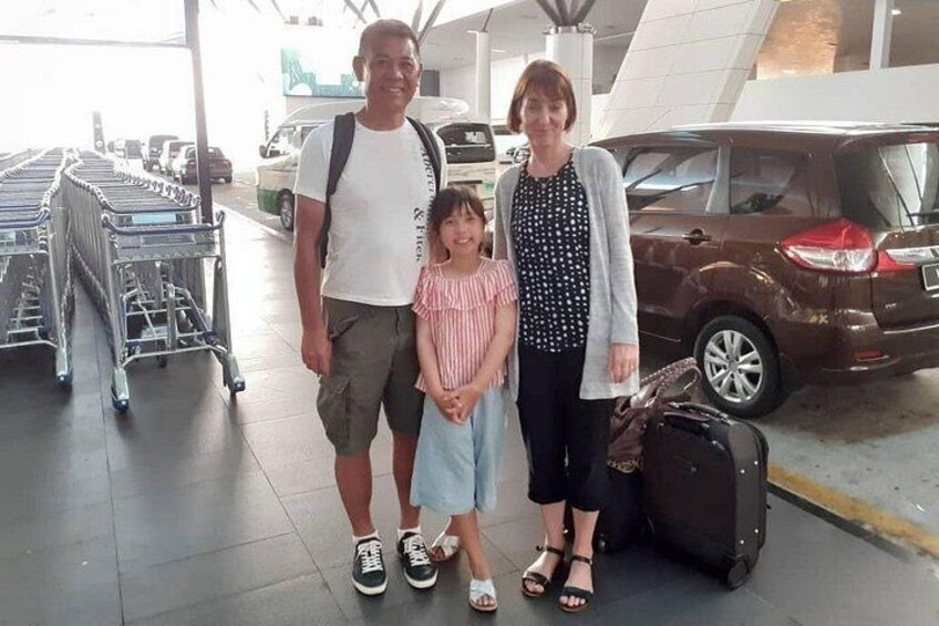 A family with a child standing in an airport terminal with luggage and shopping carts. 3