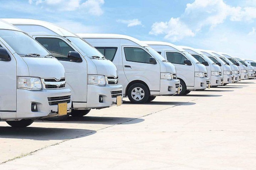 A row of white vans parked in a lot. 2