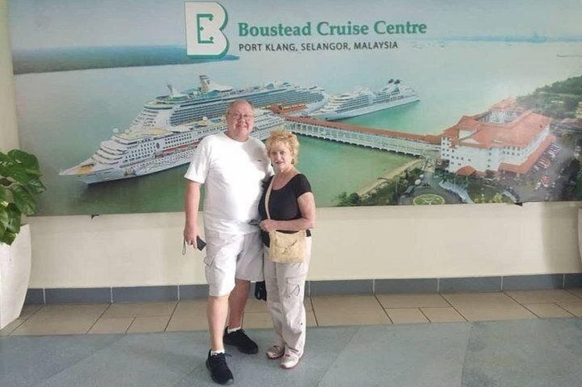 A man and a woman standing in front of a wall with a cruise ship illustration and the text 'Boustead Cruise Centre Port Klang, Selangor, Malaysia'. 1