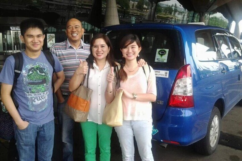 A group of people standing in front of a blue van. 2