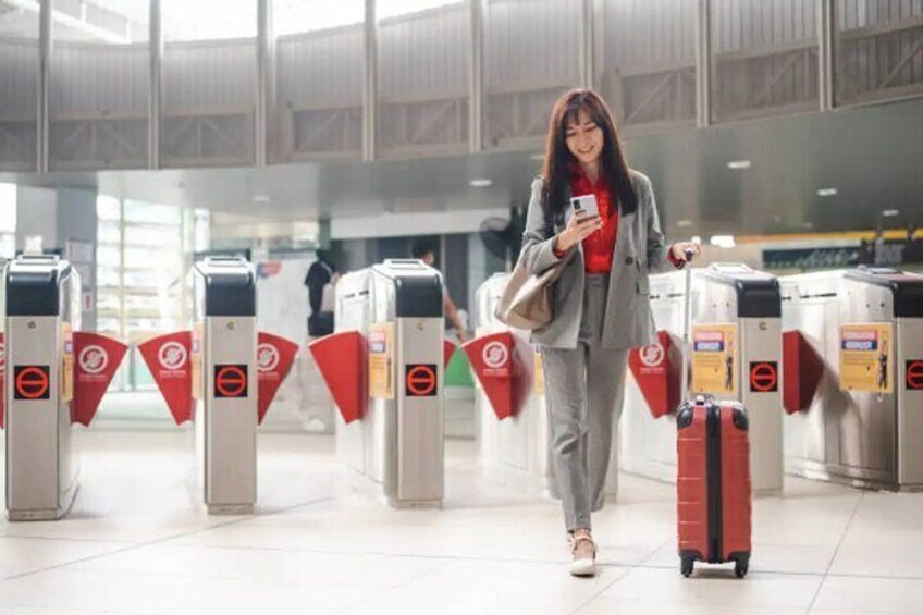 A person walking through a terminal with luggage, passing through automated turnstiles. 3