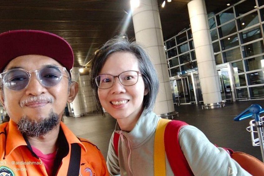 Deux personnes se trouvent dans un hall d’aéroport, qui est doté de grandes fenêtres et de colonnes. 2