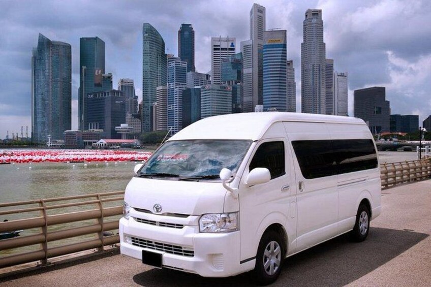 A white van parked by a waterfront with a city skyline in the background. 5
