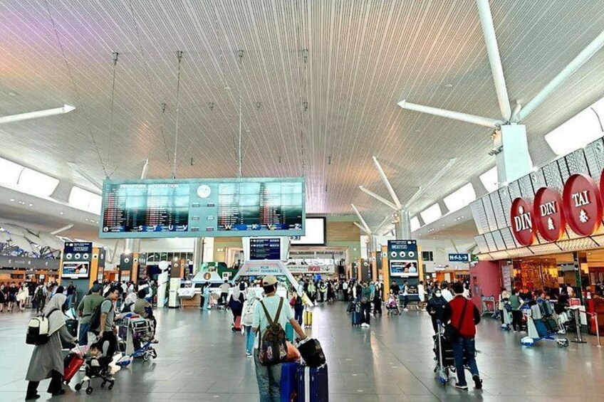 A busy airport terminal with a digital flight information display, a food court, and passengers with luggage. 3