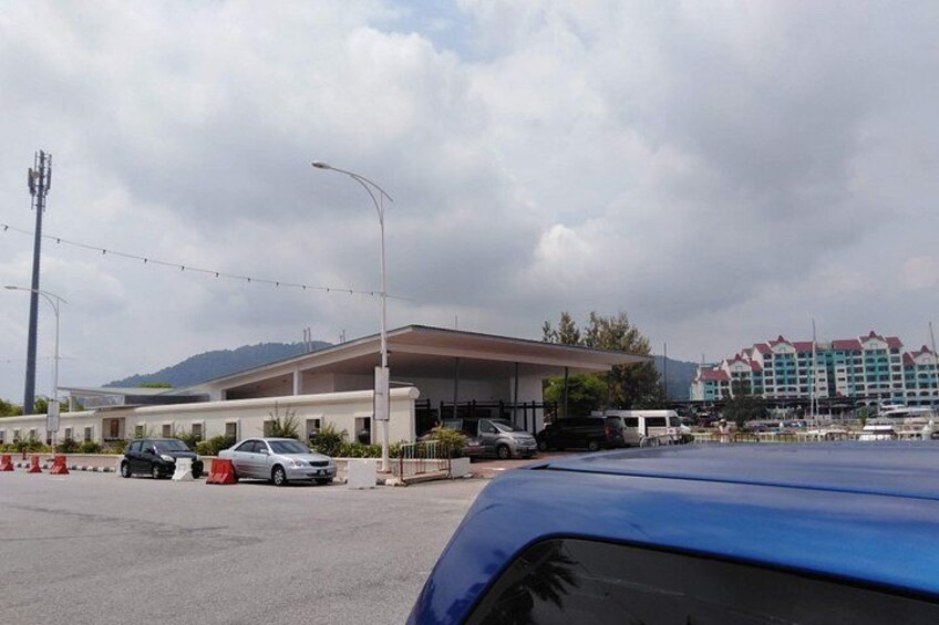 A parking lot with cars, a building with a flat roof, and a hotel in the background. 3