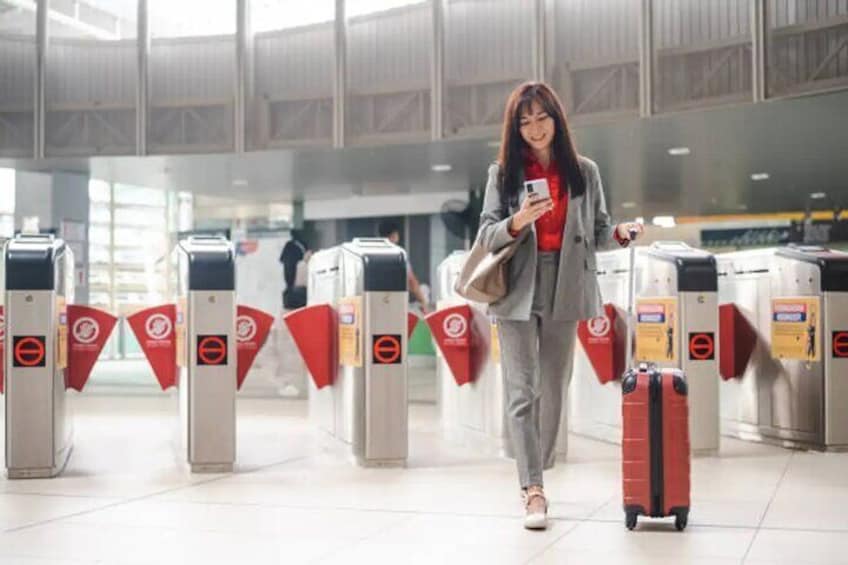 A person walking through a terminal with luggage, passing through automated turnstiles. 3