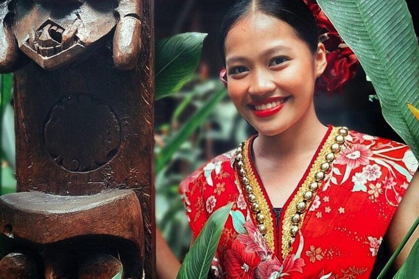 Una scultura in legno e una persona con un abito rosso a fiori. 3