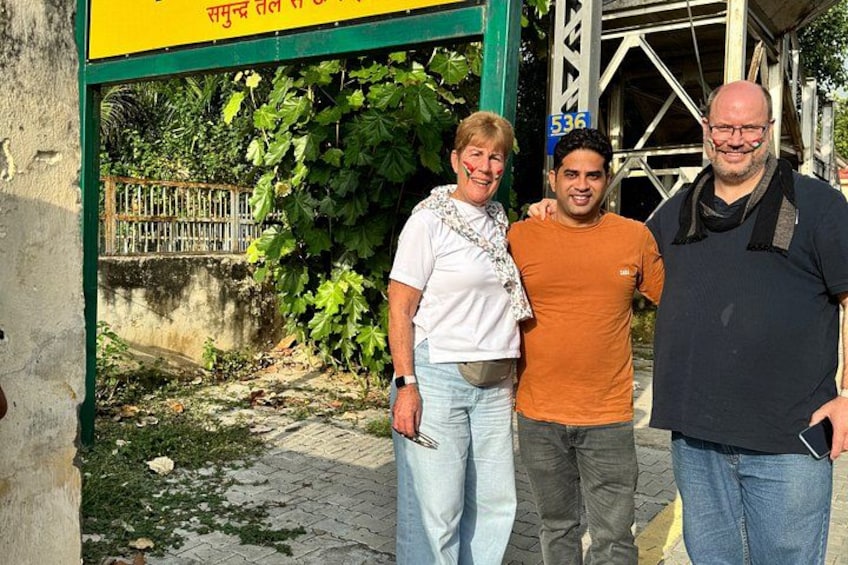 Three people standing in front of a sign with a number. 2