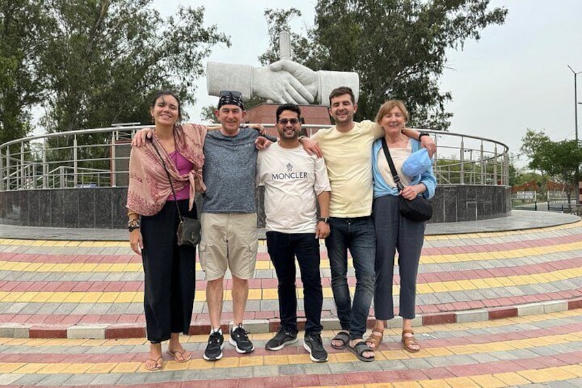 A group of people posing in front of a statue with a circular walkway behind them. 5