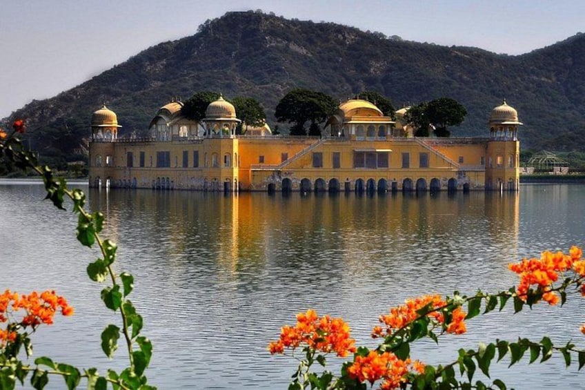 A yellow building with domes on a lake, surrounded by hills. 2