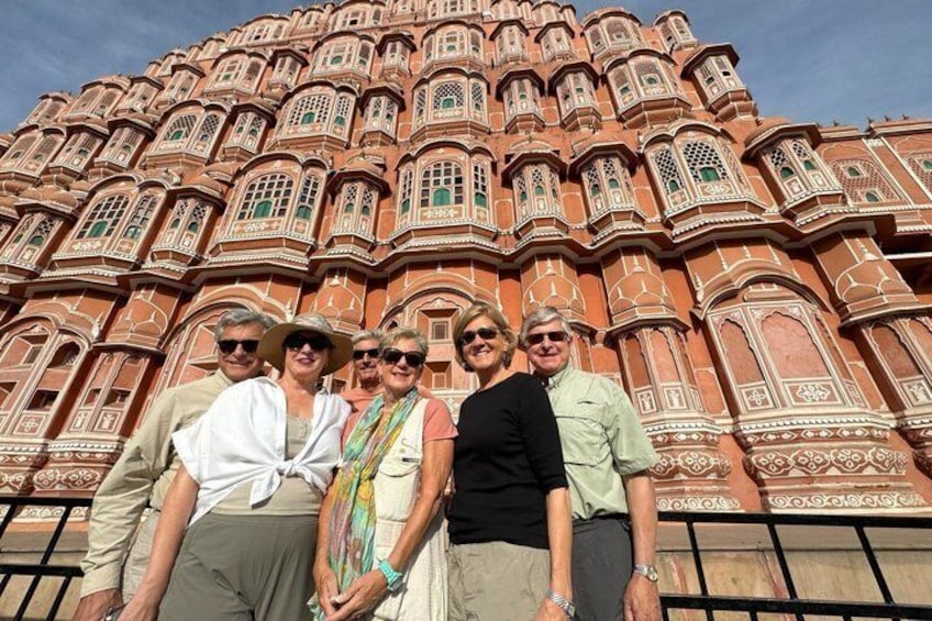 A group of people standing in front of a large, ornate building with intricate architectural details. 4