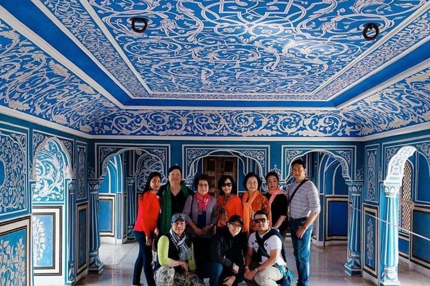 A group of people in a room with intricate blue and white patterns on the walls and ceiling. 3