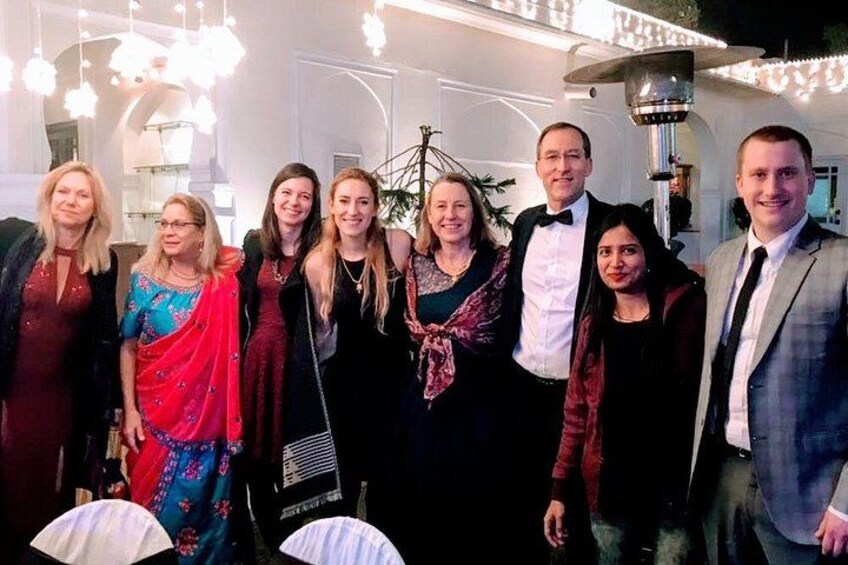A group of people posing for a photo in a well-lit indoor setting with decorative lighting and a chandelier. 4