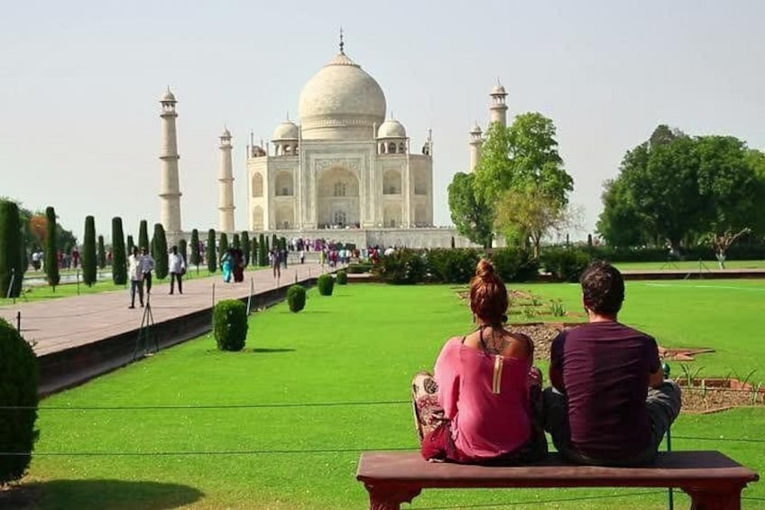 El Taj Mahal con una pareja sentada en un banco, mirándolo. 1