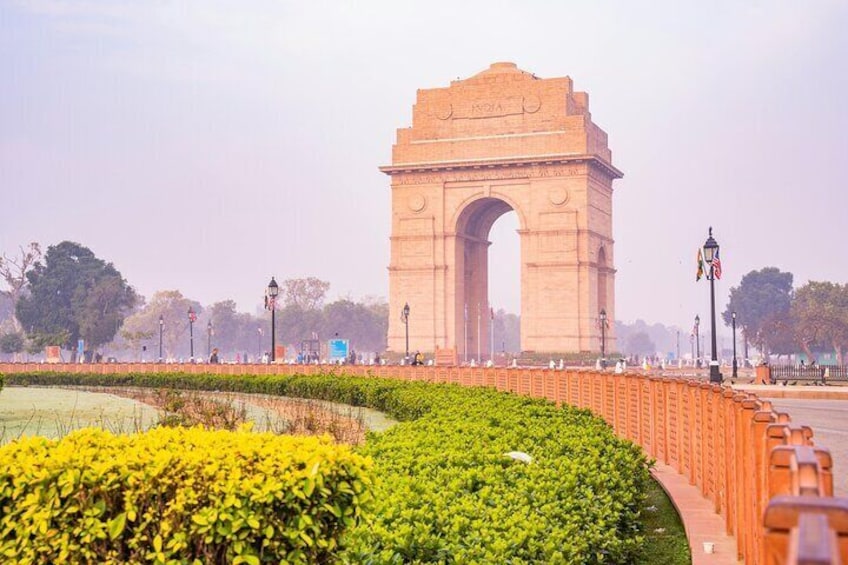The India Gate with a garden in the foreground and a clear sky. 1