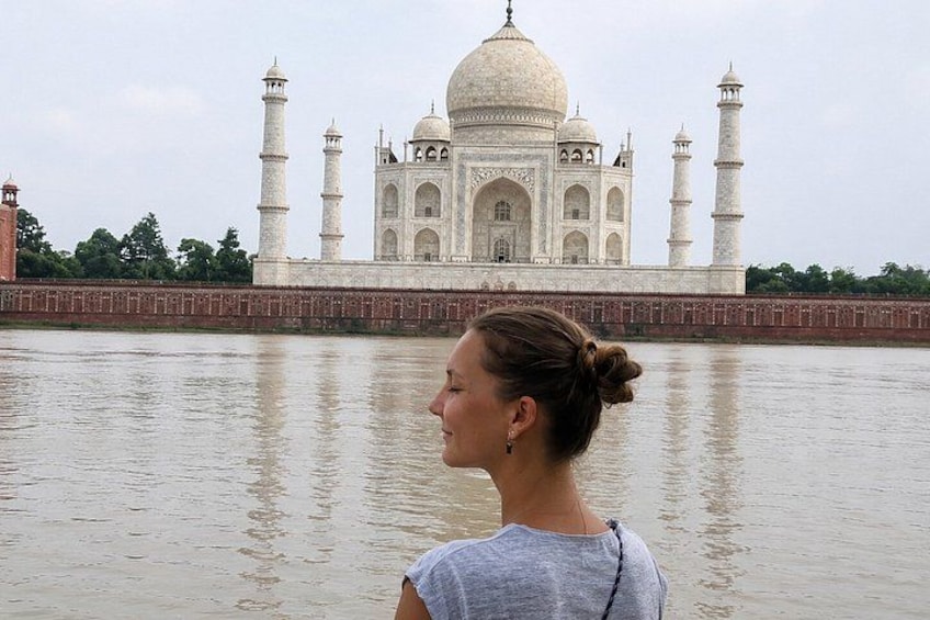 Eine Person steht vor dem Taj Mahal, im Vordergrund fließt ein Fluss. 4
