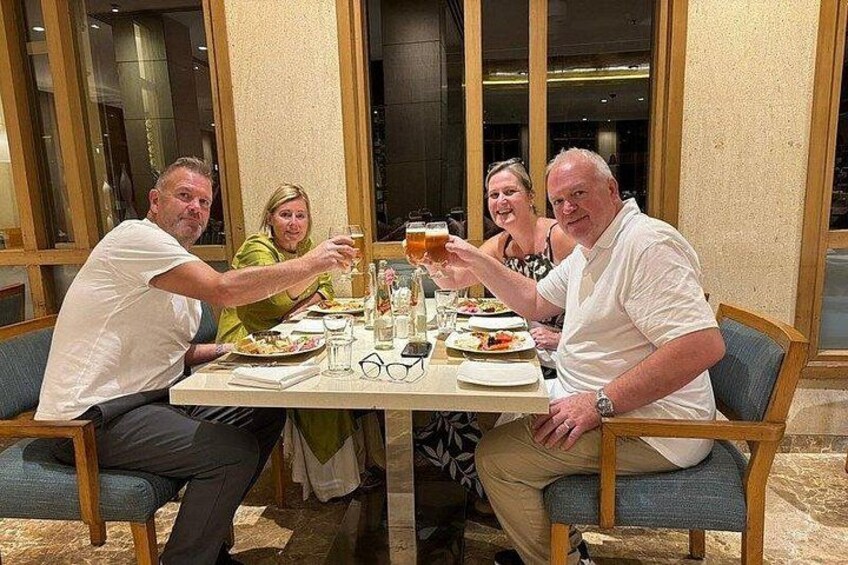 Un grupo de personas brindando alrededor de una mesa con bebidas y platos de comida. 5