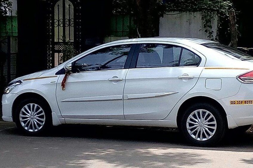 A white sedan parked on a street with a decorative gate in the background. 2