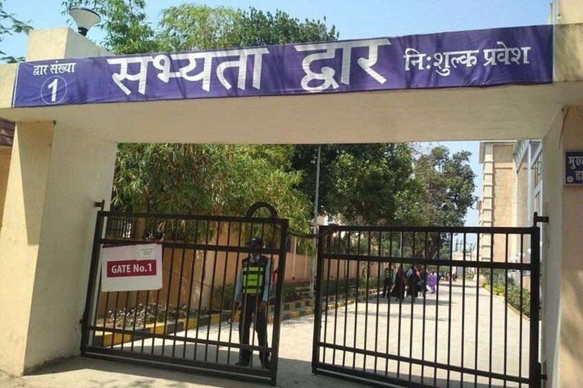 A gated entrance with a sign reading 'GATE No.1' and a banner above stating 'Sushmita Dwar' and 'N.I. Shukla Pravesh.' 2