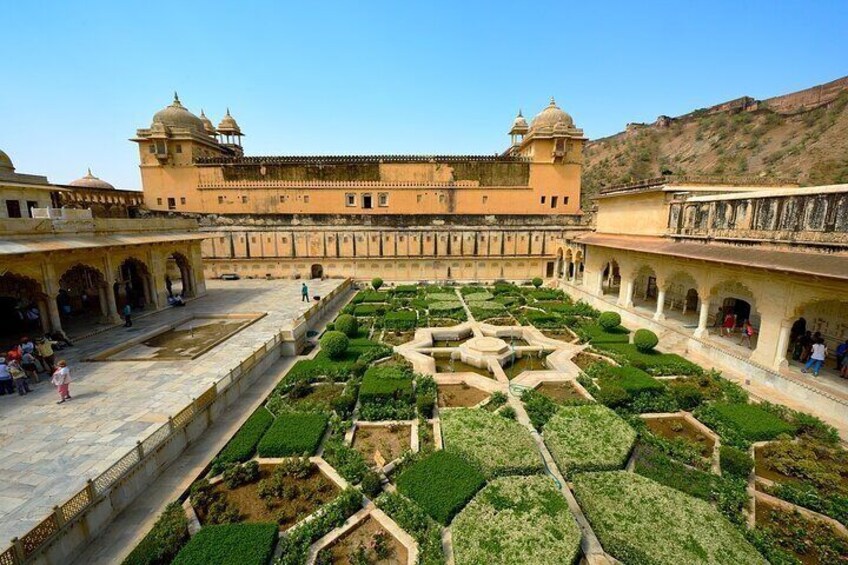 A historic building with a courtyard featuring geometric garden designs. 3
