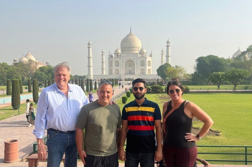 Vier Personen vor dem Taj Mahal zu sehen, mit freiem Blick auf das berühmte, weiße Marmor-Mausoleum und seine vier Minarette. 3