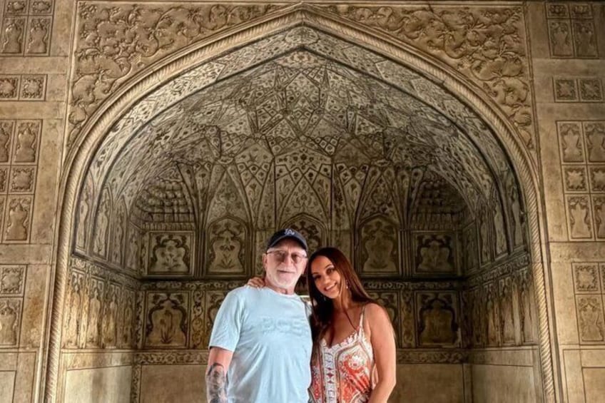 Una pareja de pie frente a un arco arquitectónico detallado con intrincados relieves. 2