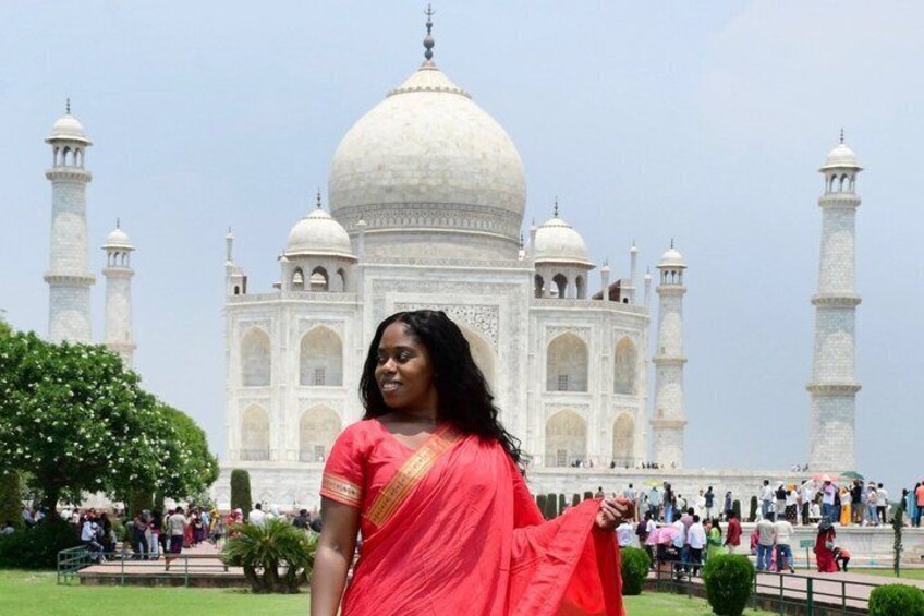 Una persona con un sari rojo de pie frente al Taj Mahal. 3