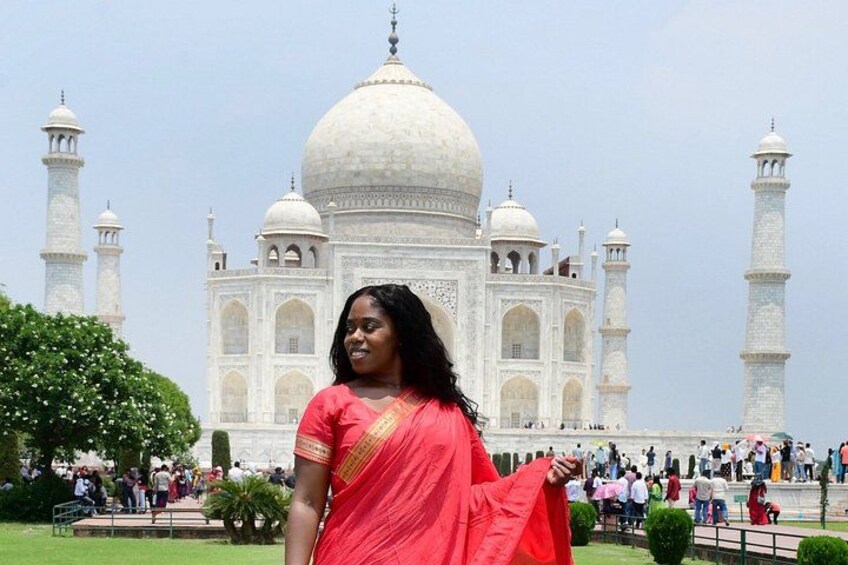 A person in a red sari standing in front of the Taj Mahal. 3