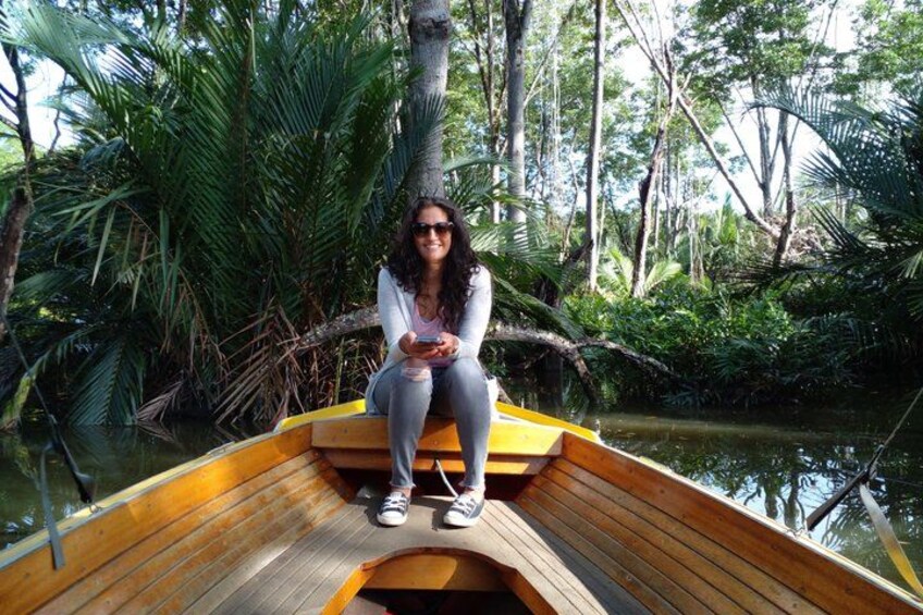 A person sitting on a wooden boat in a forested area with water. 4