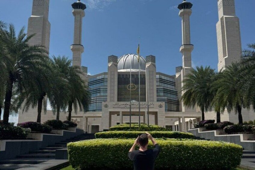 A mosque with a large dome and minarets, surrounded by palm trees and a well-maintained garden. 1
