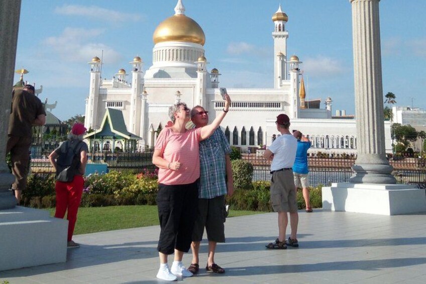 A group of people taking a photo in front of a large white building with a golden dome and minarets. 3