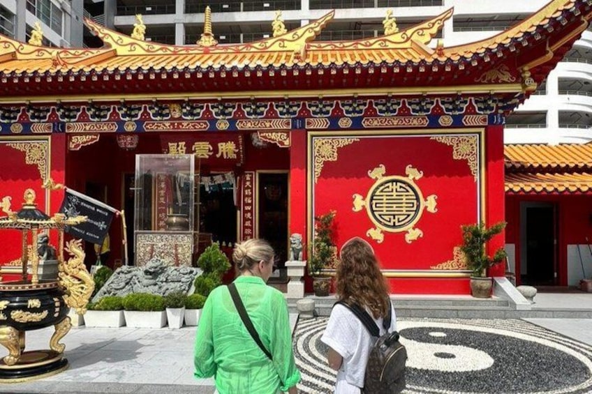 A traditional Chinese temple with ornate architecture, a large circular emblem, and a stone lion statue. 4