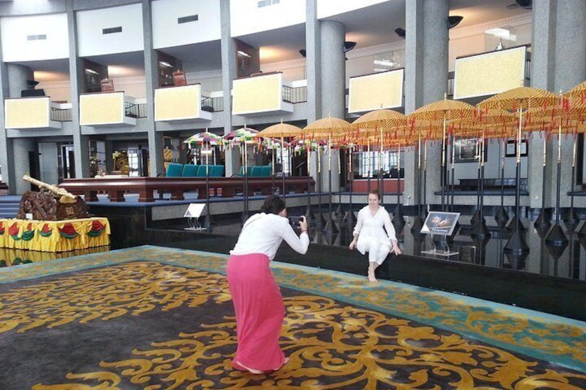 Un hall con alfombra estampada, una mujer fotografiando y una mujer caminando. 4