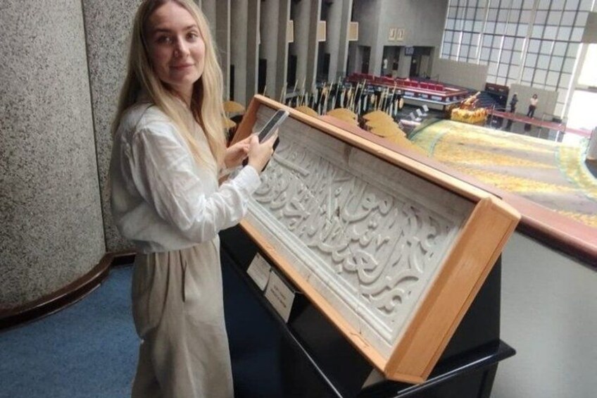 A person holding a framed artwork in a room with a large window and a building in the background. 5