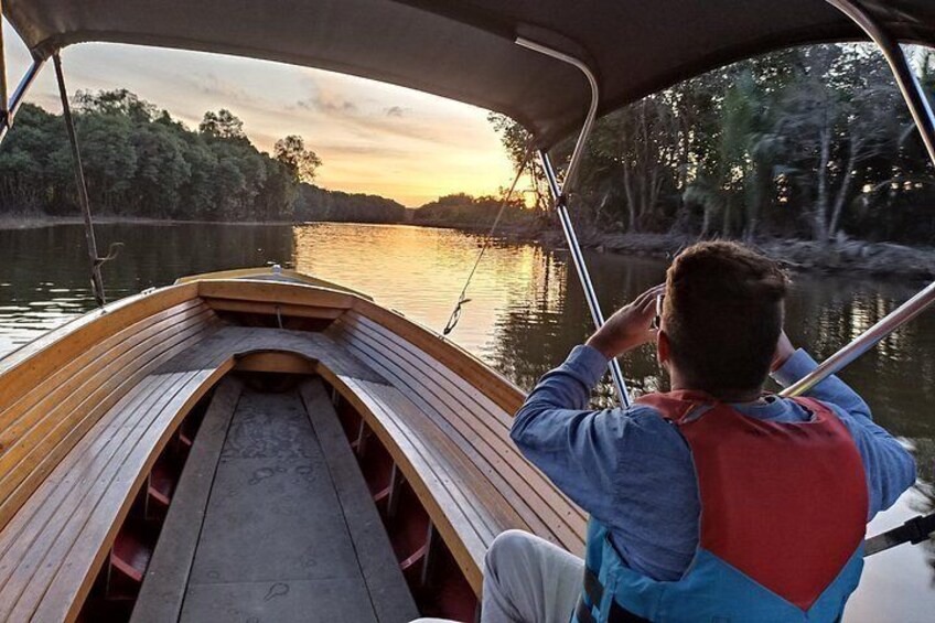 A wooden boat on calm water with a person wearing a life jacket. 1