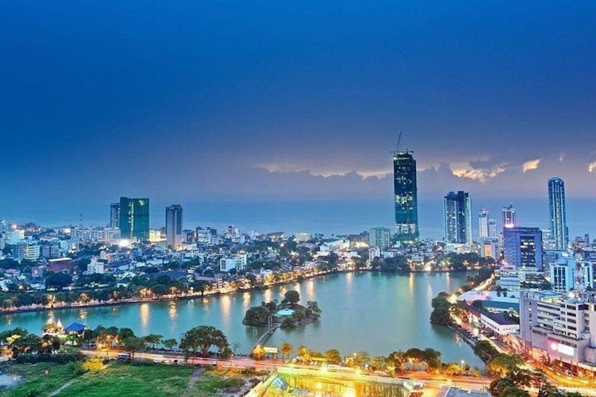 A cityscape at dusk with illuminated buildings, a river, and a park area. 5