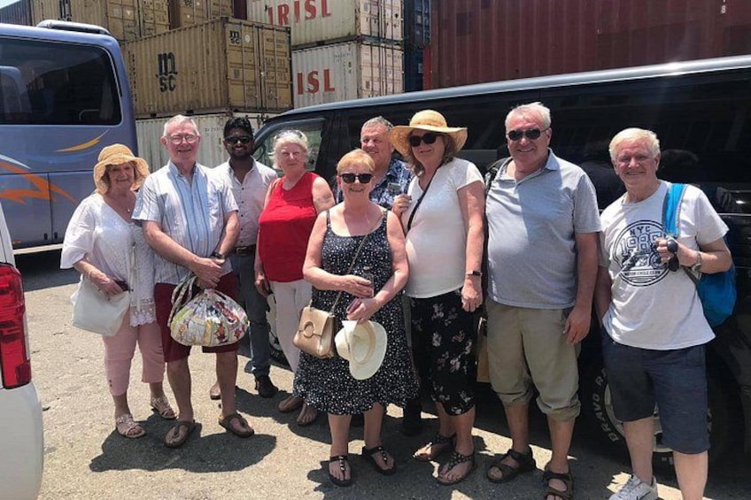A group of people standing in front of a shipping container and a van. 1