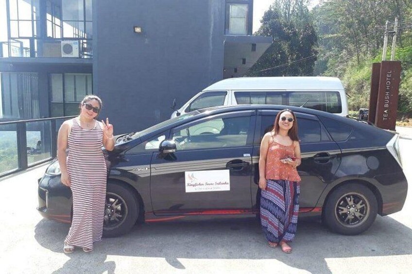 Dos personas de pie junto a un coche con un cartel que dice 'Kingfisher Hotel'. 5