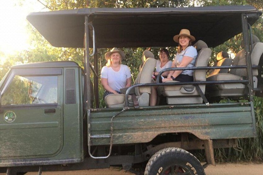 A green safari vehicle with three passengers. 5