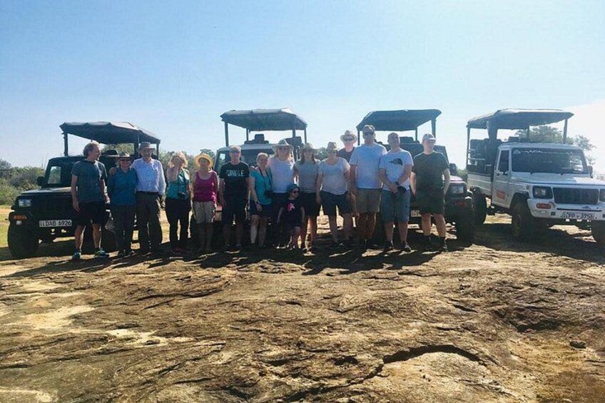 A group of people standing in front of a dirt ground with three vehicles. 4