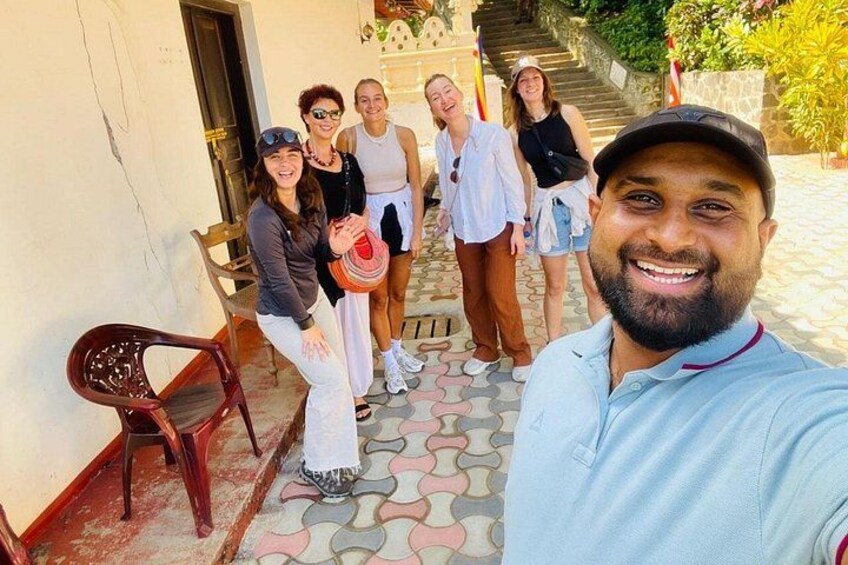 A group of people on a tiled pathway with a chair and a building in the background. 5