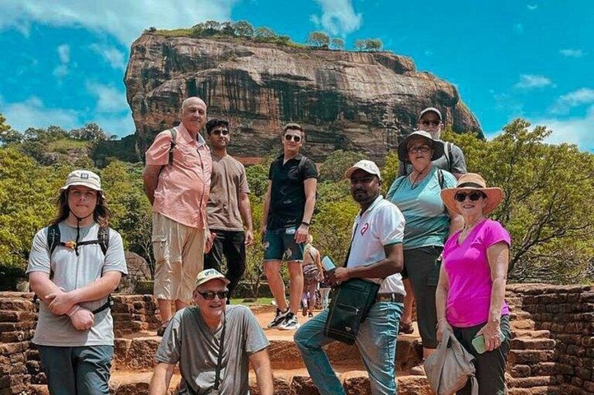 A group of people standing in front of a large rock formation. 1